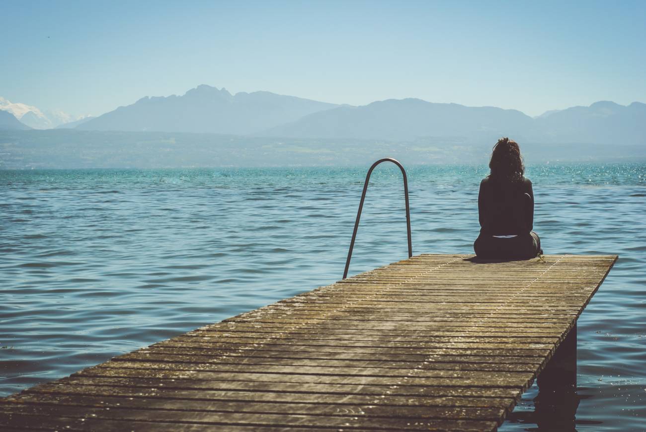 a person looking out at the lake from a pier