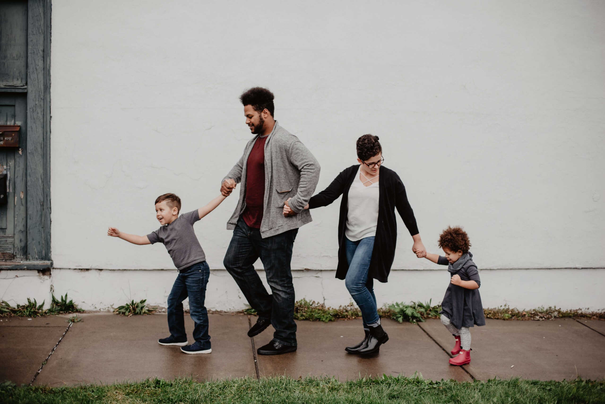 a woman, man and two children holding hands and walking outside