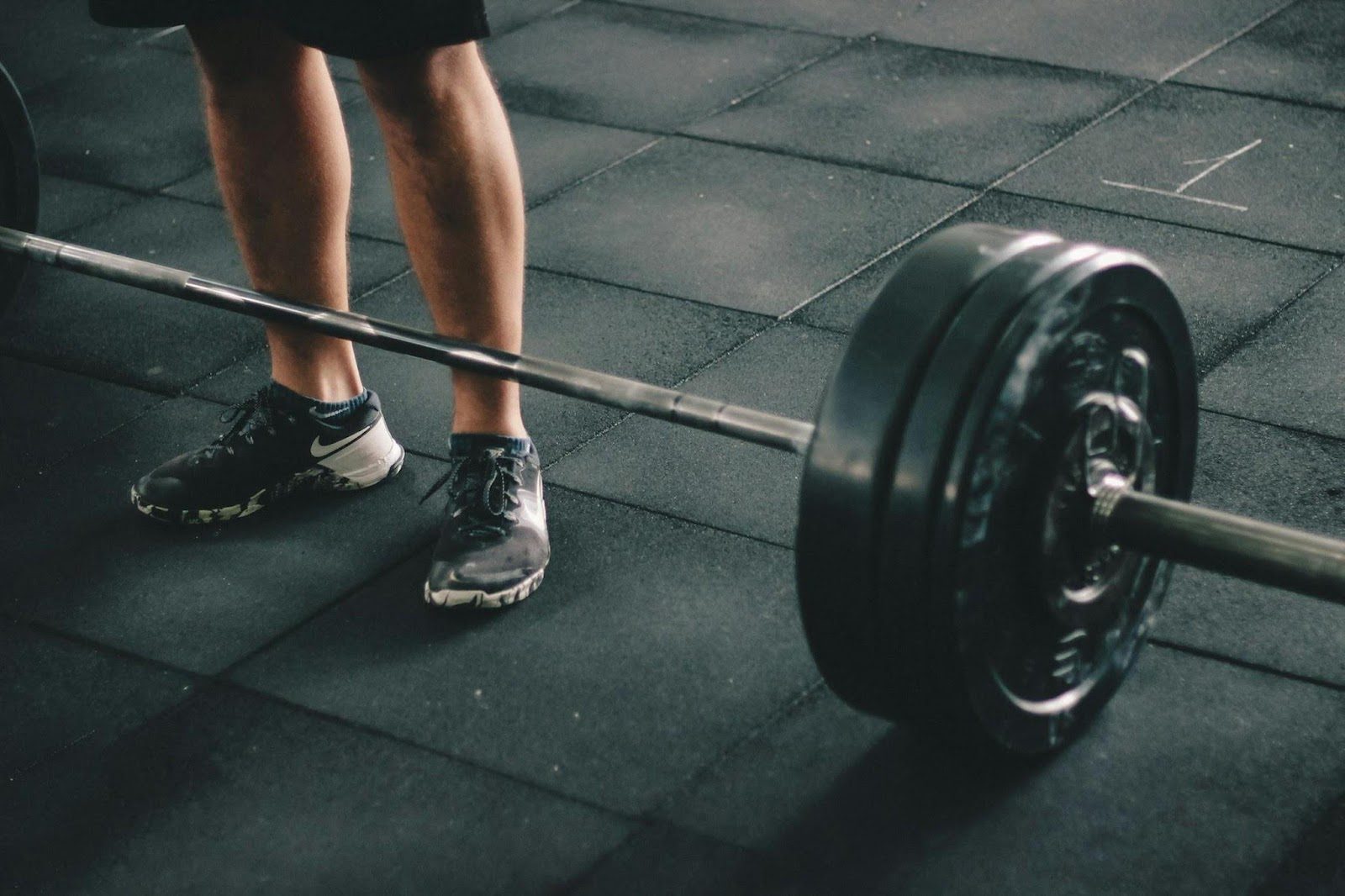 man's legs standing next to dumbbell in gym