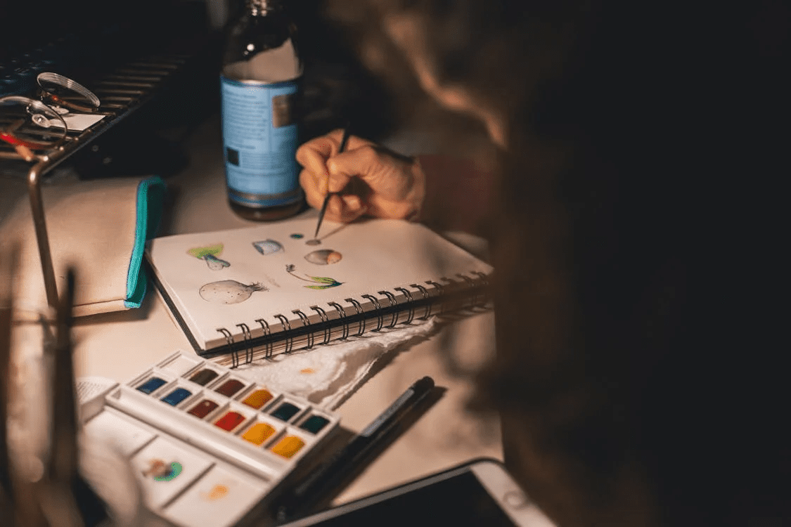 person doing art on sketchpad in low lighting