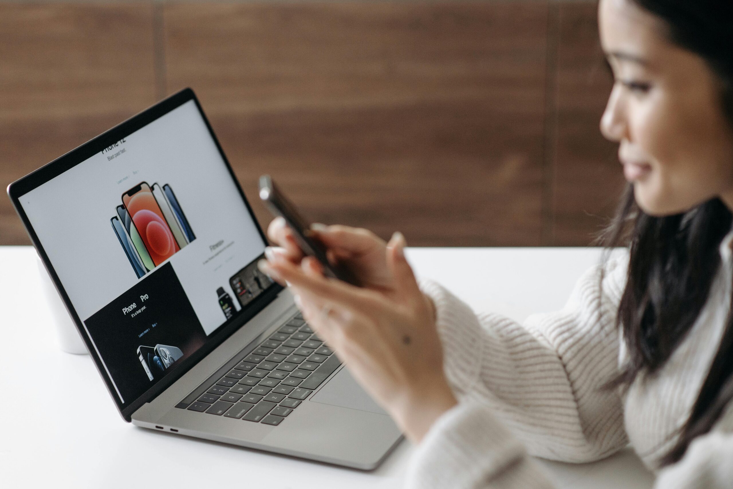 A Woman using a Smartphone next to a laptop