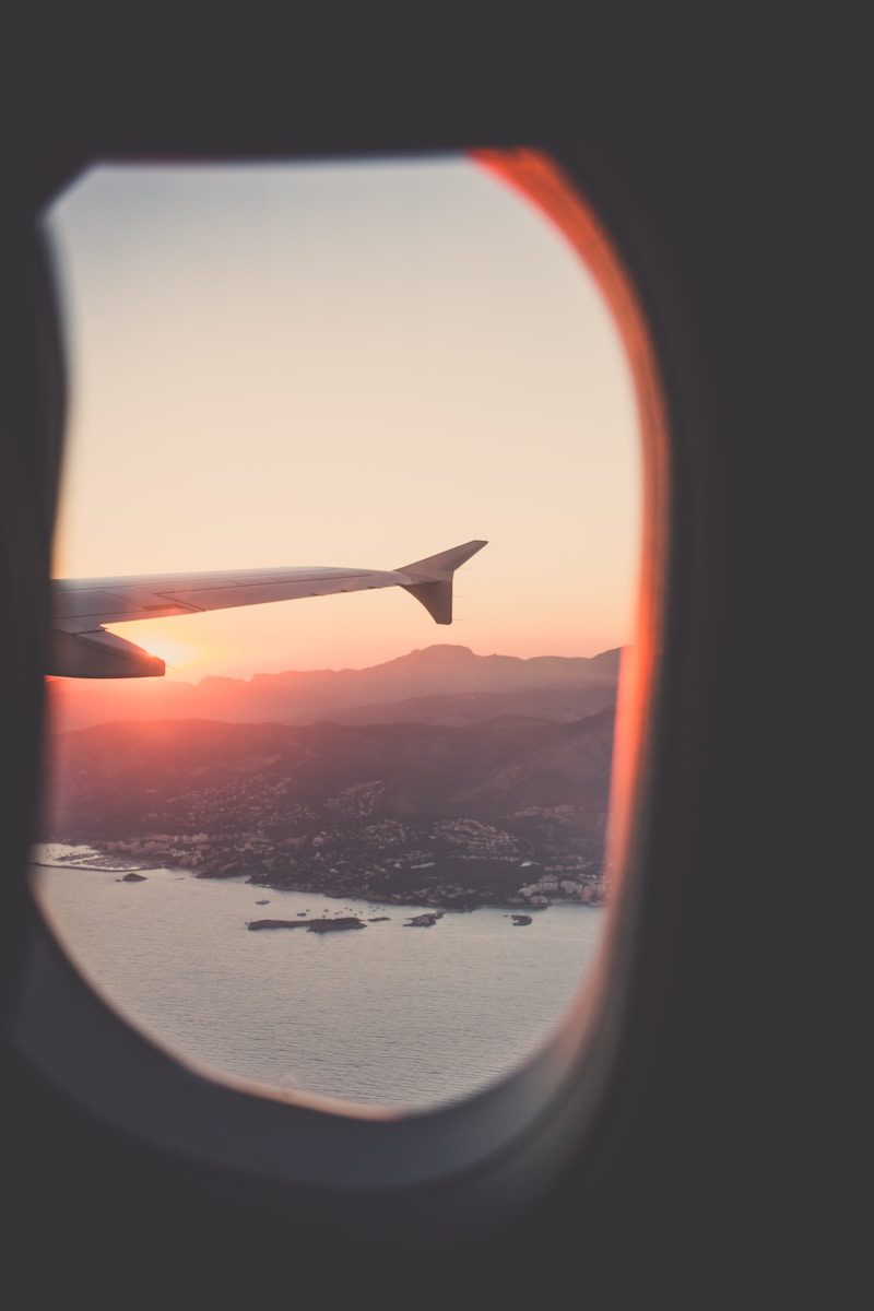 view of plane wing and land at sunset out of plane window