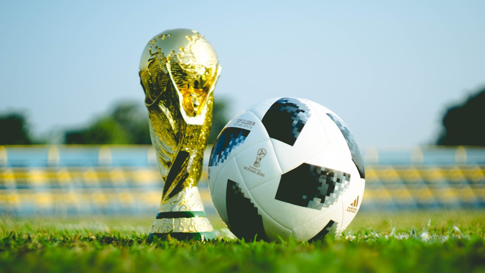 gold trophy and football on football pitch