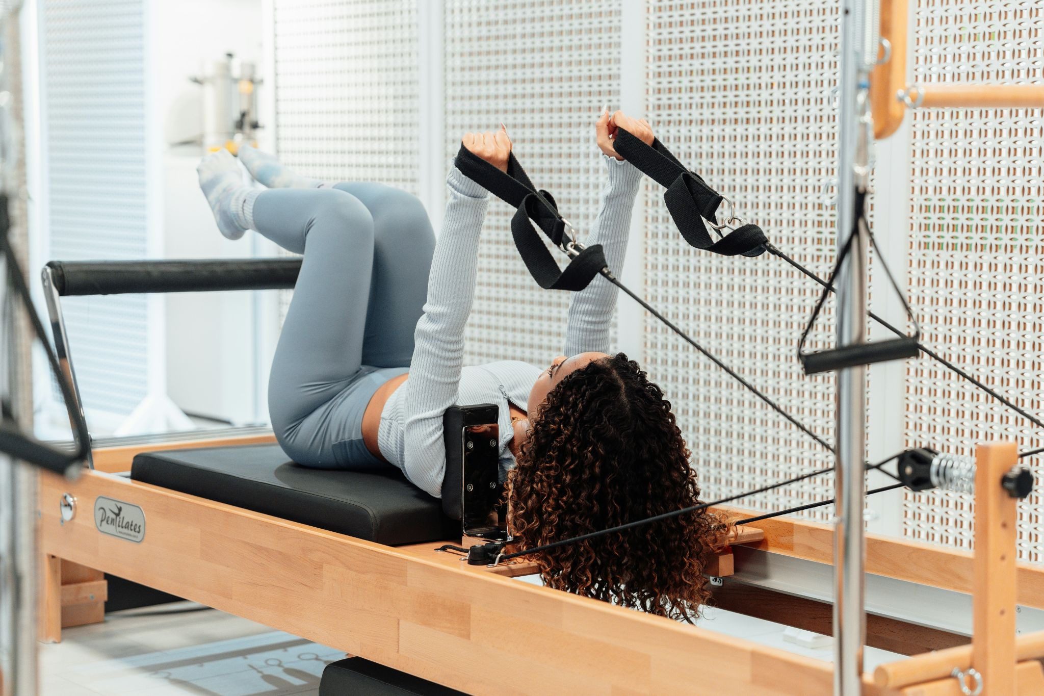 woman on reformer pilates bench with legs up and bent